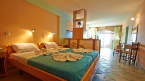 Una camera d'hotel con un letto di legno, biancheria verde, un piccolo tavolino di legno, uno specchio e vista sulla sala da pranzo.