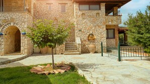 Un edificio in pietra con un cortile, un piccolo albero e un vialetto piastrellato.
