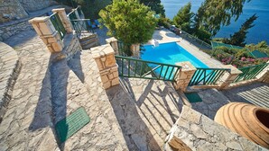 Una scala in pietra conduce a una zona piscina con vista sul mare.