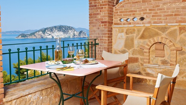 Un tavolo con vista sul mare, un forno a mattoni e una sedia.