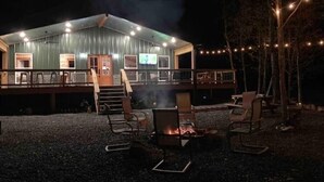 A rustic cabin with a deck, outdoor seating, and a fire pit.