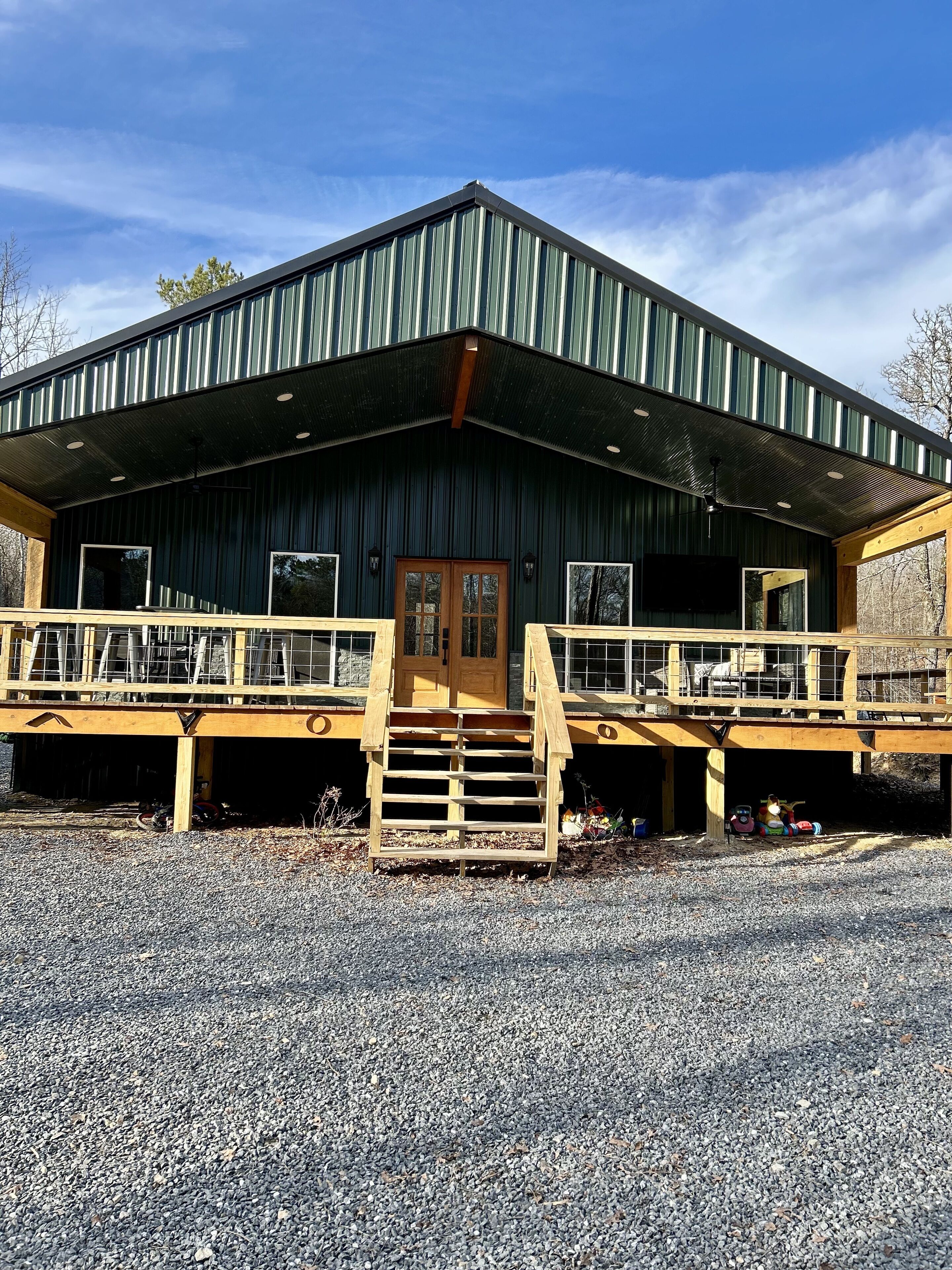 A rustic building with a metal roof, wooden deck, and a central staircase leading to a door.
