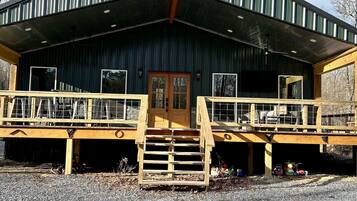 A rustic building with a metal roof, wooden deck, and a central staircase leading to a door.