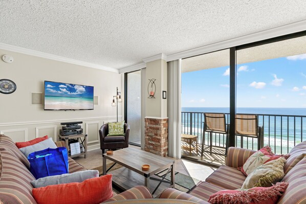 A living room with a television, a fireplace, and a view of the ocean. - Beach Haven! 2BR 2BA Sleeps 6! Coastal Paradise Awaits! (Panama City Beach)