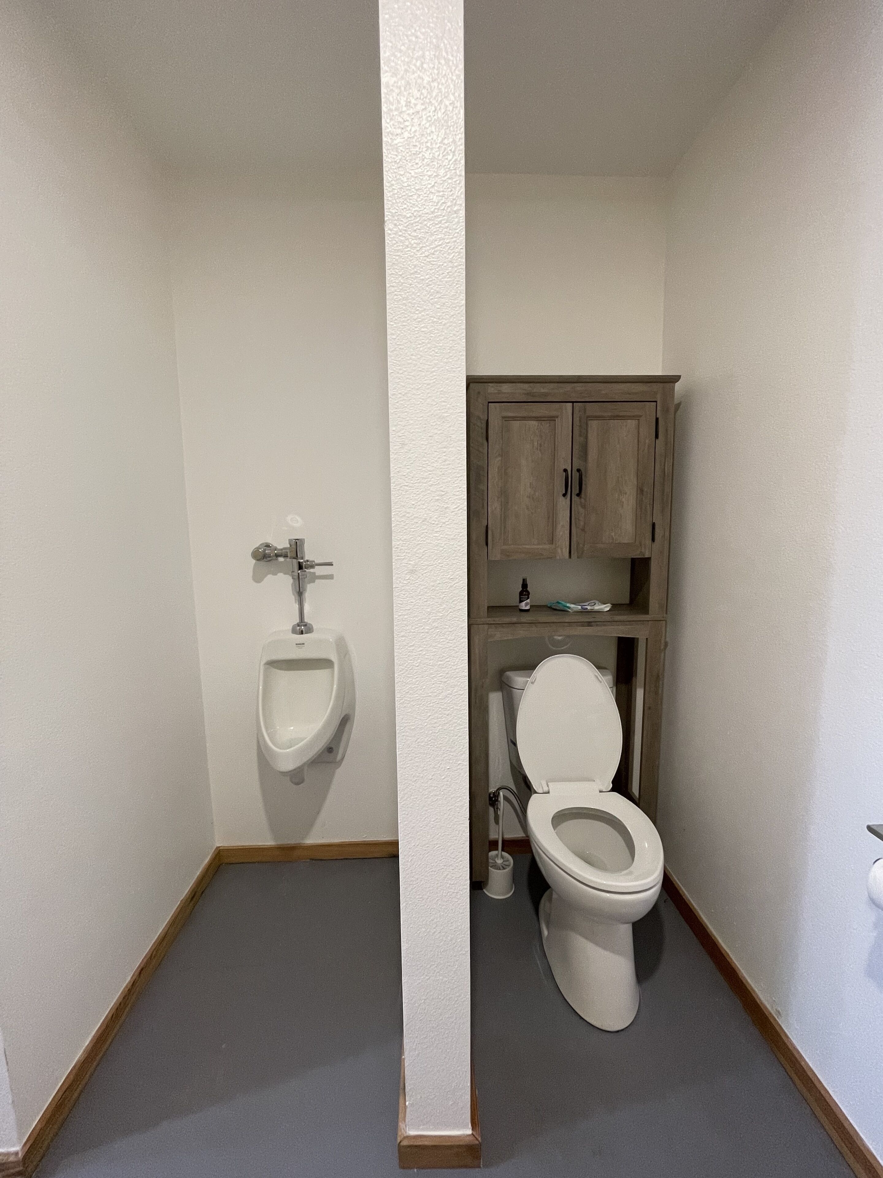 Une salle de bain avec un urinoir blanc, des toilettes et des meubles en bois.