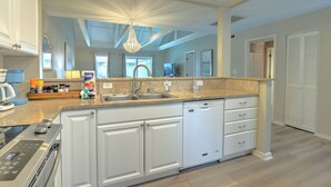 A modern kitchen with a built-in dishwasher, a double sink, and a large island with storage drawers.