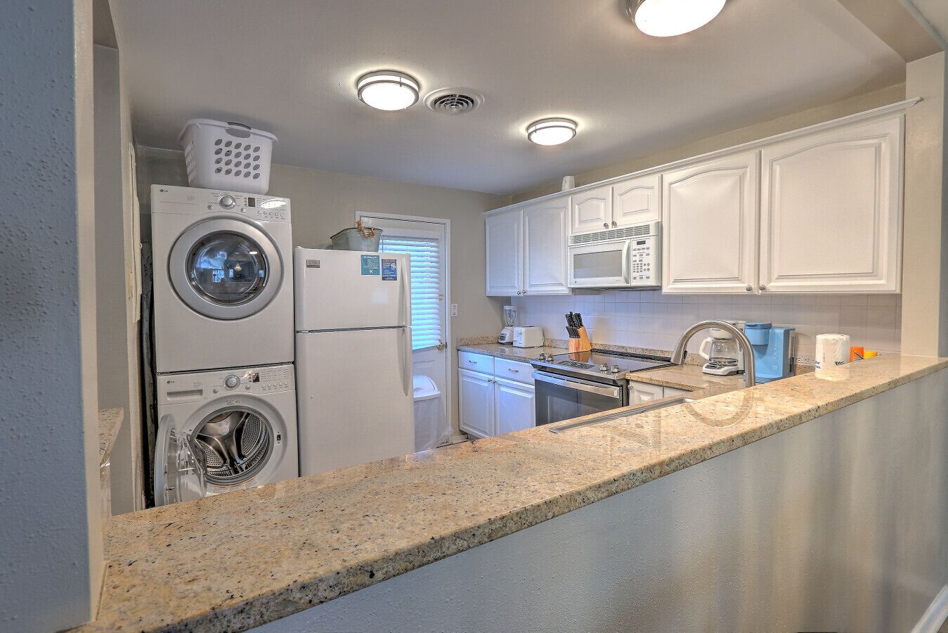 A compact kitchen with a washing machine, a microwave, and a sink.