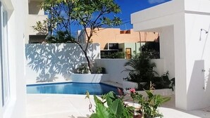 Un espace extérieur moderne doté d’une piscine, de murs blancs et de plantes en pot.