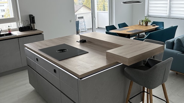 A modern kitchen with a central island, a dining area with a table and chairs, and a sofa in a living space. - Vollausgestattete Wohnung im Neubau (Waldshut-Tiengen)