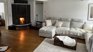 Ein modernes Wohnzimmer mit Kamin, einer Couch und Holzboden.