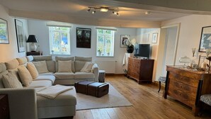 Ein Wohnzimmer mit Sofa, Holzboden, Fernseher und Kommode.