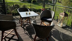 Eine Terrasse im Freien mit Korbmöbeln, einem Tisch und einer Laterne.