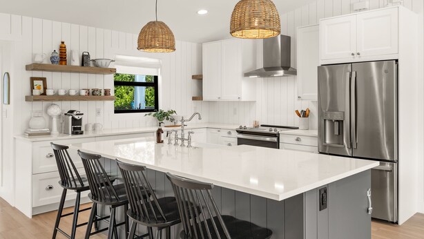 A modern kitchen with white cabinetry, a large island with bar stools, stainless steel appliances, and wicker pendant lights. - Shorebird Cottage - heated pool - 1 mi from beach (Bonita Springs)