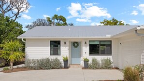 A single-story house with a front door, two windows on the first floor, and a garage on the right. - Shorebird Cottage - heated pool - 1 mi from beach (Bonita Springs)