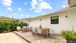 A patio with a wooden table and chairs, surrounded by potted plants and a brick floor. - Shorebird Cottage - heated pool - 1 mi from beach (Bonita Springs)