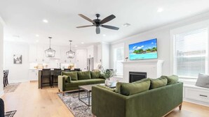 Una sala de estar moderna con un sofá verde, una zona de comedor y una chimenea.
