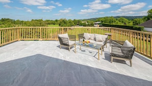 A terrace with a glass table, two wicker chairs, and a sofa. - 2 bedroom accommodation in Broadway, near Cotswolds (Broadway, near Cotswolds)