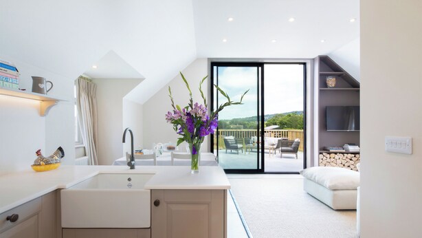A modern kitchen with a sink, cabinets, and a dining area with a table and chairs. - 2 bedroom accommodation in Broadway, near Cotswolds (Broadway, near Cotswolds)