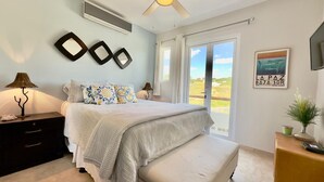 Une chambre à coucher comprenant un lit, des tables de chevet, une fenêtre et un climatiseur fixé au mur.