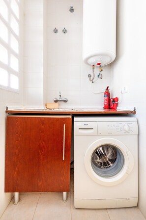 A compact laundry area with a Bosch washing machine, a wooden cabinet, and a water heater.