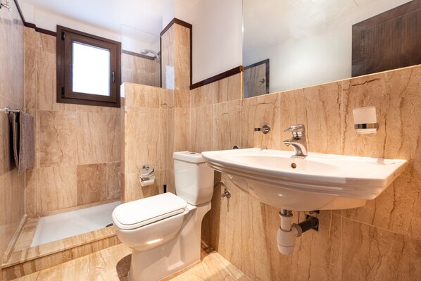 A modern bathroom with a toilet, sink, and shower. - Finca San Antonio | Apartment with pool views near Mijas (Mijas Pueblo)