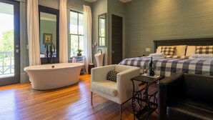 A bedroom with a large bed, a bathtub, and a seating area. - Auburn Bed and Breakfast (Lafayette)