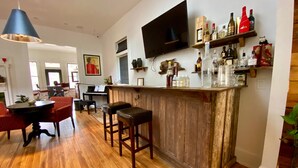 A spacious living area with a wooden bar, red chairs, a piano, and a television mounted on the wall. - Auburn Bed and Breakfast (Lafayette)