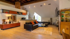 A spacious living area with a high ceiling, a black leather sofa, a wooden cabinet, and a dining table. - Auburn Bed and Breakfast (Lafayette)