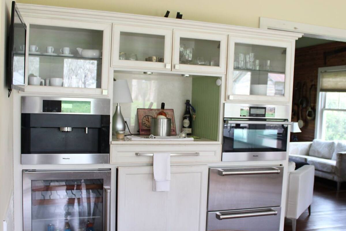 A modern kitchen with built-in appliances, white cabinetry, and a glass dining table.