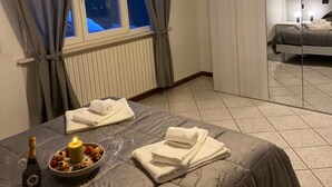 A bedroom with a bed, a bedside table with a lamp, a window with curtains, and a view of trees outside. - Appartamento a Lucca (Lucca)