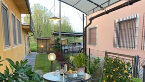 A covered patio area with a table set for dining, surrounded by potted plants and a small garden. - Appartamento a Lucca (Lucca)