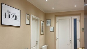 A hallway with a wooden bench, framed pictures on the wall, and a tiled floor. - Appartamento a Lucca (Lucca)