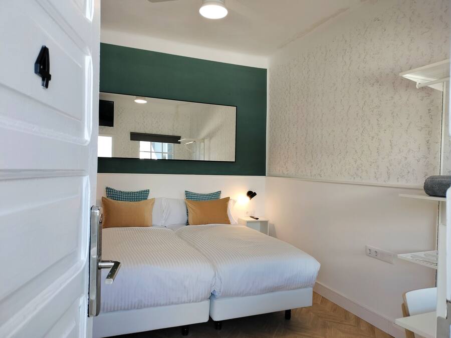 Una camera da letto con un letto, un comodino, uno specchio e una mensola.