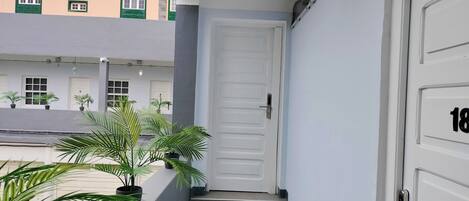 A building with a white door, a staircase, and potted plants.