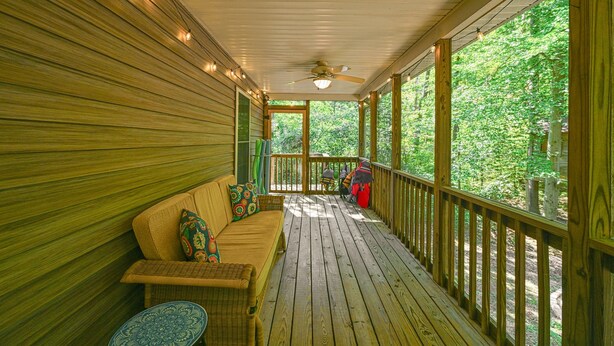 Une terrasse en bois avec un canapé et une table, donnant sur une zone boisée.
