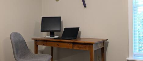 A workspace with a desk, chair, laptop, and monitor.