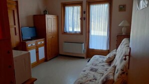 A small, furnished room with a bed, a television, a cabinet, and a radiator. - Appartement au Pied des Pistes du Col du Rousset (Saint-Agnan-en-Vercors)