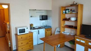 A compact kitchen with a microwave, sink, and wooden cabinets. - Appartement au Pied des Pistes du Col du Rousset (Saint-Agnan-en-Vercors)