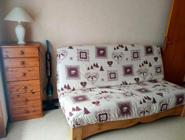 Un dormitorio con cama, cómoda de madera y lámpara.