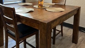 A dining table with four chairs, a candle, and a placemat.