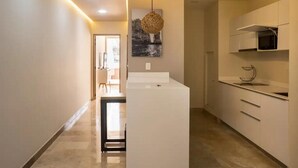 Une cuisine moderne avec des meubles blancs, un îlot central et un luminaire suspendu.