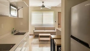 Une cuisine moderne dotée d’un four encastré, d’un ventilateur de plafond et d’une fenêtre avec des stores.
