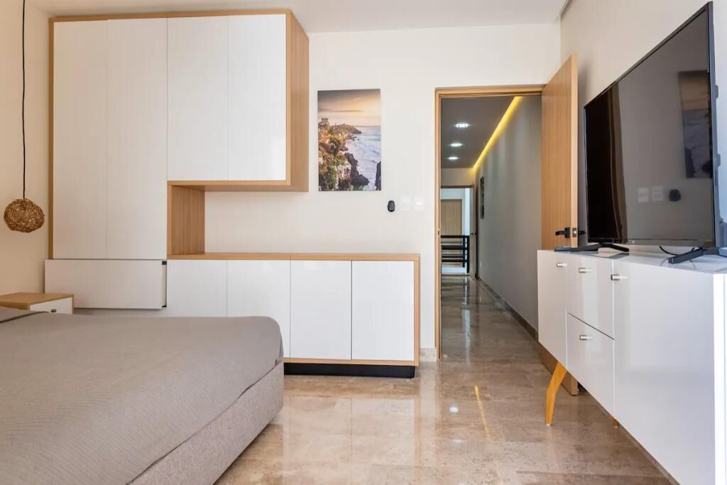 Een moderne slaapkamer met een bed, een televisie en een kledingkast.
