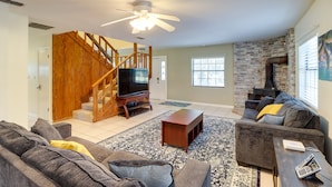 A living room with a staircase, a fireplace, and a TV. - Lake Days & Golf Outings: Summerfield Group Escape (Summerfield)