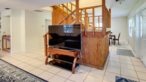 A modern living room with a wooden entertainment center, a staircase, and a dining area. - Lake Days & Golf Outings: Summerfield Group Escape (Summerfield)