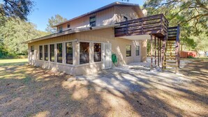 A two-story house with a covered porch, a wooden deck, and a staircase leading to an upper level. - Lake Days & Golf Outings: Summerfield Group Escape (Summerfield)