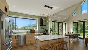 A modern kitchen with a large island, stainless steel appliances, and a view of the outdoors. - SOL® Catskills Mnt view, Sauna, Hot Tub, Fire Pit, Min to Plattekill & Belleayre (New Kingston)
