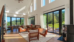 A spacious living room with a large brown leather sofa, a wooden chair, and a fireplace. - SOL® Catskills Mnt view, Sauna, Hot Tub, Fire Pit, Min to Plattekill & Belleayre (New Kingston)