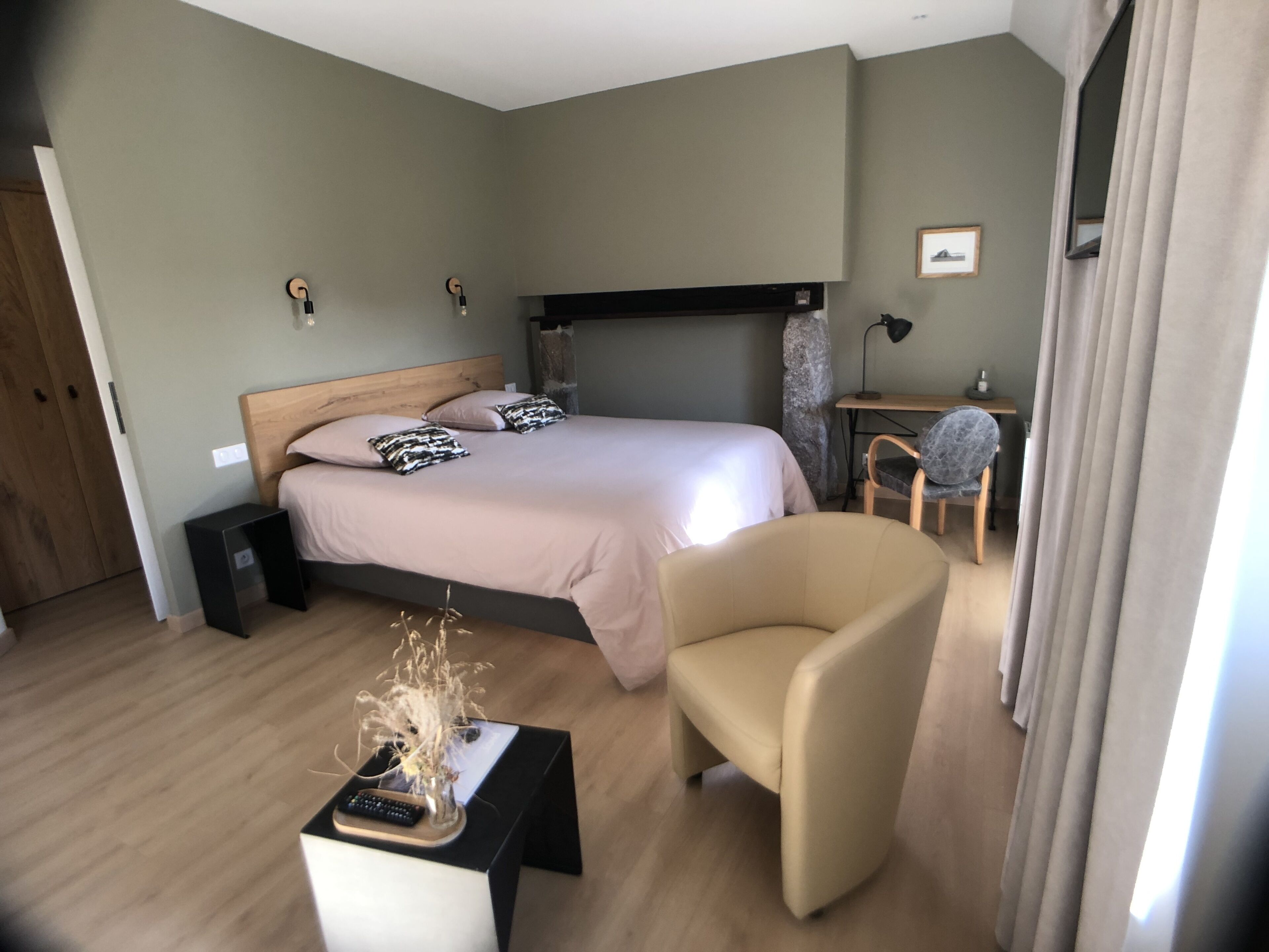 A modern bedroom with a bed, a desk, a chair, and a small table with a vase.