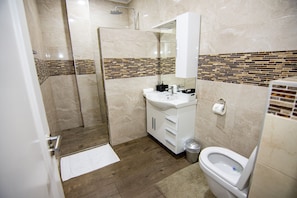 A bathroom with a shower, sink, toilet, and a mirror. - Empire 1 Celinastraat Paramaribo (Paramaribo)